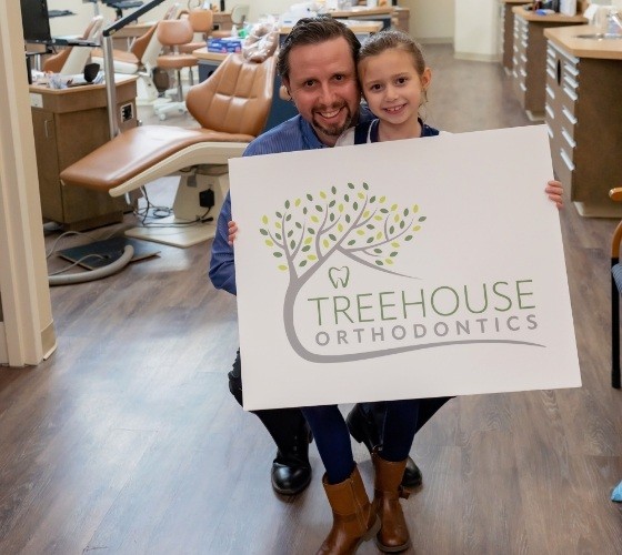 Greenfield orthodontist with young girl holding sign that says Treehouse Orthodontics