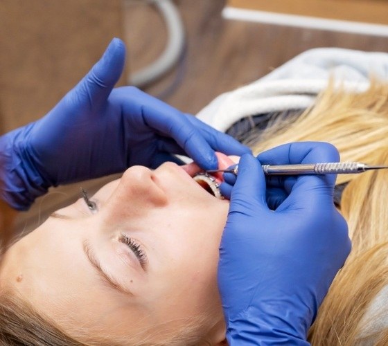 Orthodontist examining the mouth of a young woman with braces in Amherst